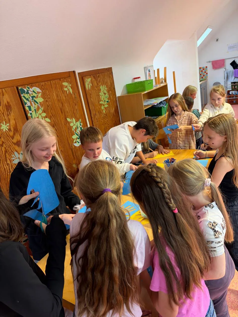 Kinder gestalten gemeinsam blaue und gelbe Papierhände