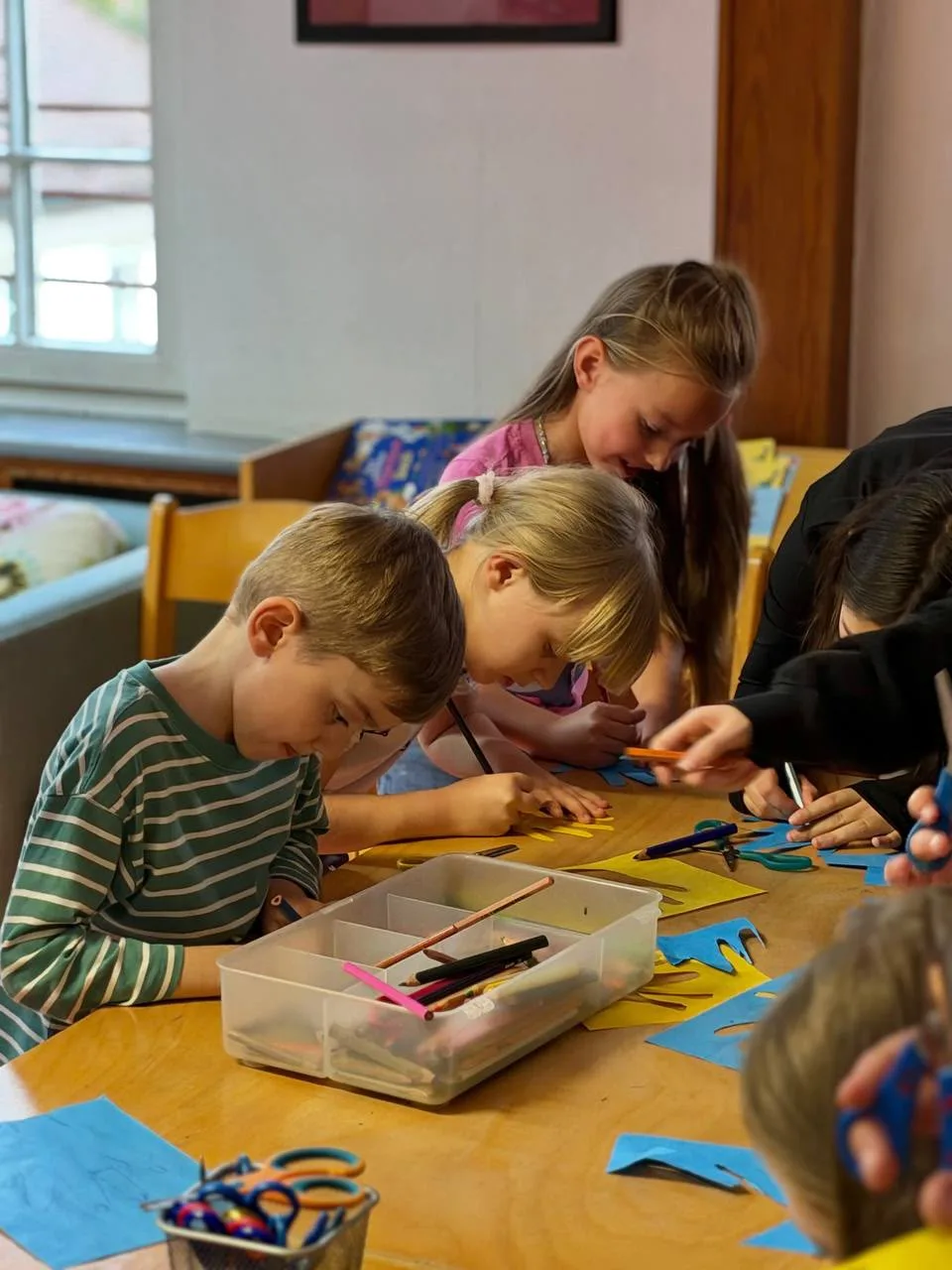 Kinder arbeiten konzentriert an einem Basteltisch